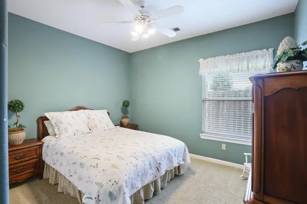 a bed sitting in a bedroom next to a window and a potted plant