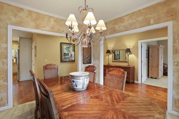 a dining room with wooden floor a chandelier a wooden table and chairs