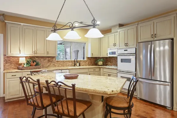 a kitchen with kitchen island a stove a table and chairs in it