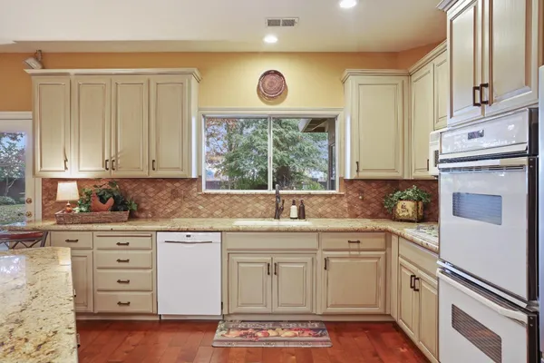 a kitchen with granite countertop white cabinets and white appliances