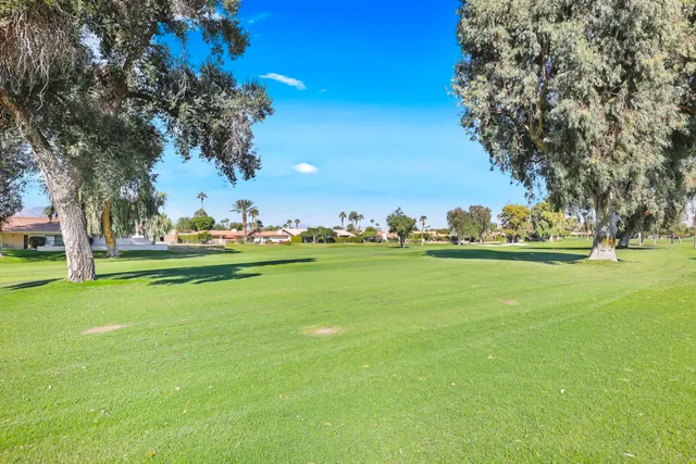 a front view of a house with garden and trees