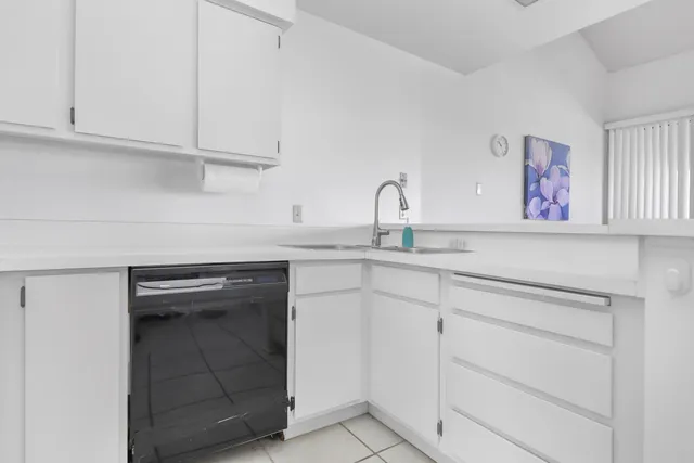 a kitchen with white cabinets and sink