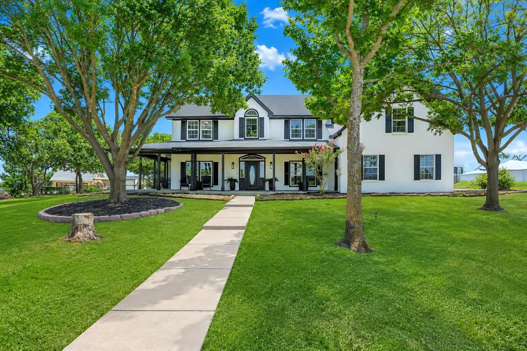 3817 Ganzer Road West Denton, TX 76207 - Photo 1 of 40 The front of the farmhouse faces north, where the light stays even across the lawn and shade trees. The walkway leads straight to the porch, framed in black trim and tall windows that give the home its crisp, modern look. The attached garage sits off to the right, keeping the front view open and uncluttered — a calm, straightforward entry that feels intentional from the moment you arrive.