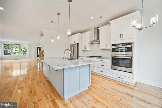 a large kitchen with stainless steel appliances kitchen island granite countertop a large stove a sink dishwasher and a refrigerator with wooden floor