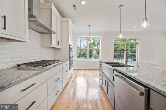 a kitchen with stainless steel appliances granite countertop a stove a sink and a wooden floors