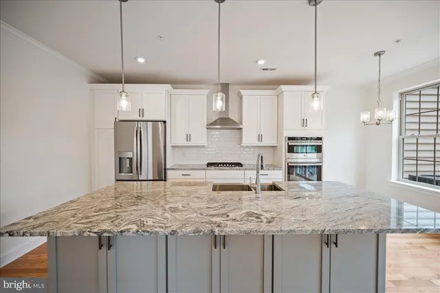 a kitchen with stainless steel appliances granite countertop a sink a refrigerator and a granite counter tops