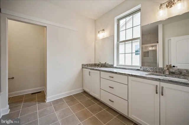 a bathroom with a granite countertop sink a mirror and a shower