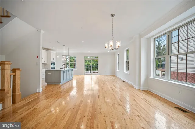 a view of a kitchen with kitchen island a sink wooden floor and a large window