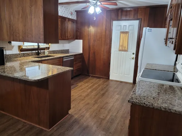 a kitchen with granite countertop wood cabinets stainless steel appliances a sink and window