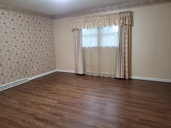 an empty room with wooden floor & windows