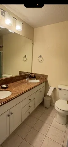 a spacious bathroom with a granite countertop sink a toilet and a mirror