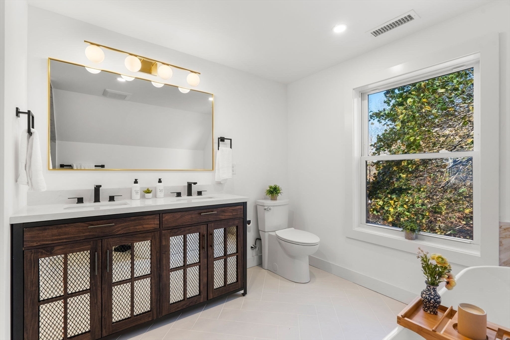 45 Charles Street Wakefield, MA 01880 - Photo 36 of 42 a bathroom with a toilet a sink a mirror a window and vanity