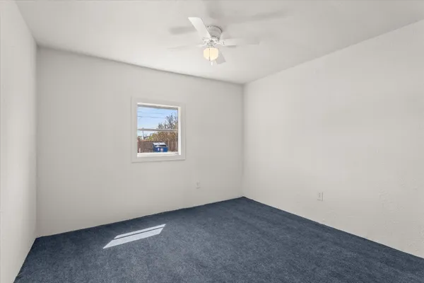an empty room with a ceiling fan and window