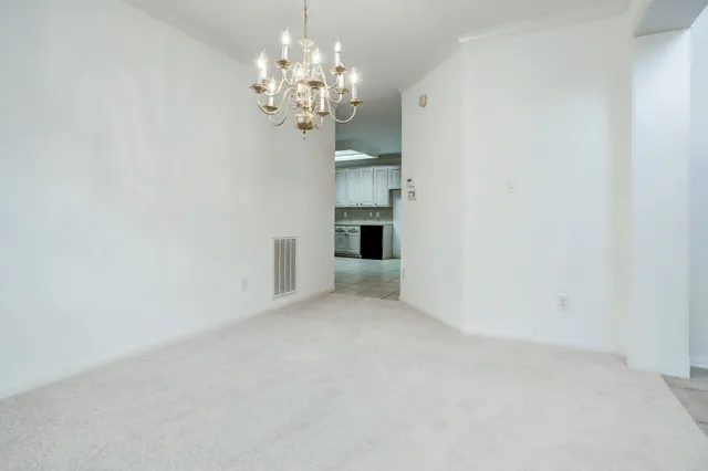 a view of a room with a chandelier fan and kitchen view