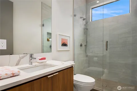 a bathroom with a granite countertop sink a toilet and shower