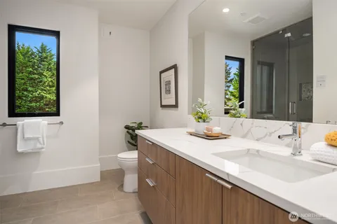 a bathroom with a granite countertop sink a toilet a large mirror and shower