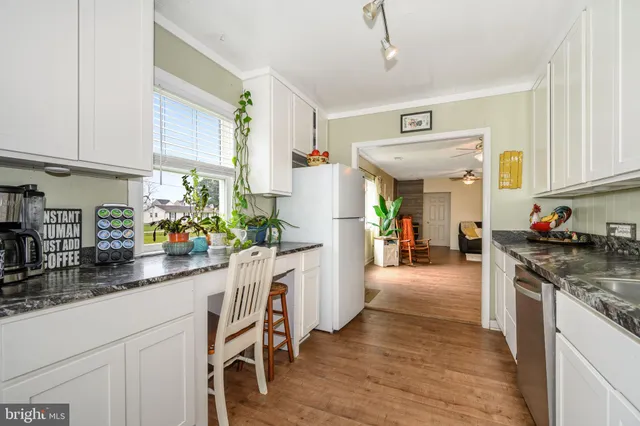 a kitchen with stainless steel appliances granite countertop a refrigerator a sink dishwasher and white cabinets with wooden floor