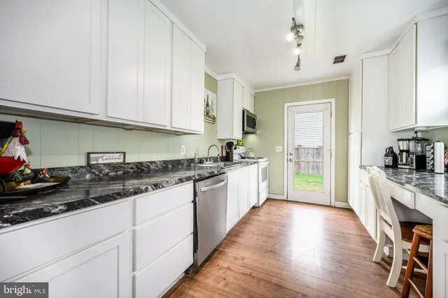 a large kitchen with granite countertop a stove top oven a sink a dining table and chairs with wooden floor