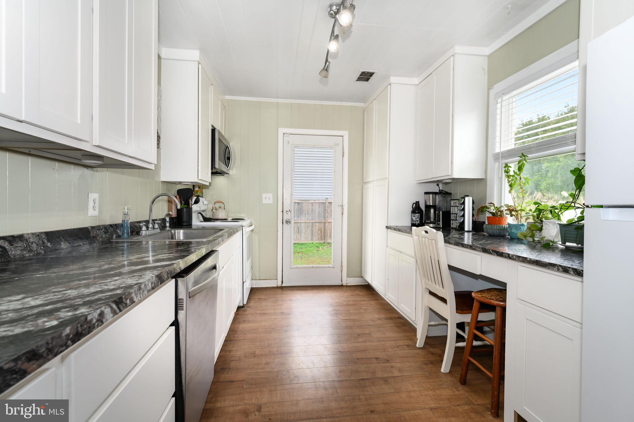 204 Long Point Road Stevensville, MD 21666 - Photo 16 of 34 a kitchen with granite countertop a stove a sink and white cabinets with wooden floor
