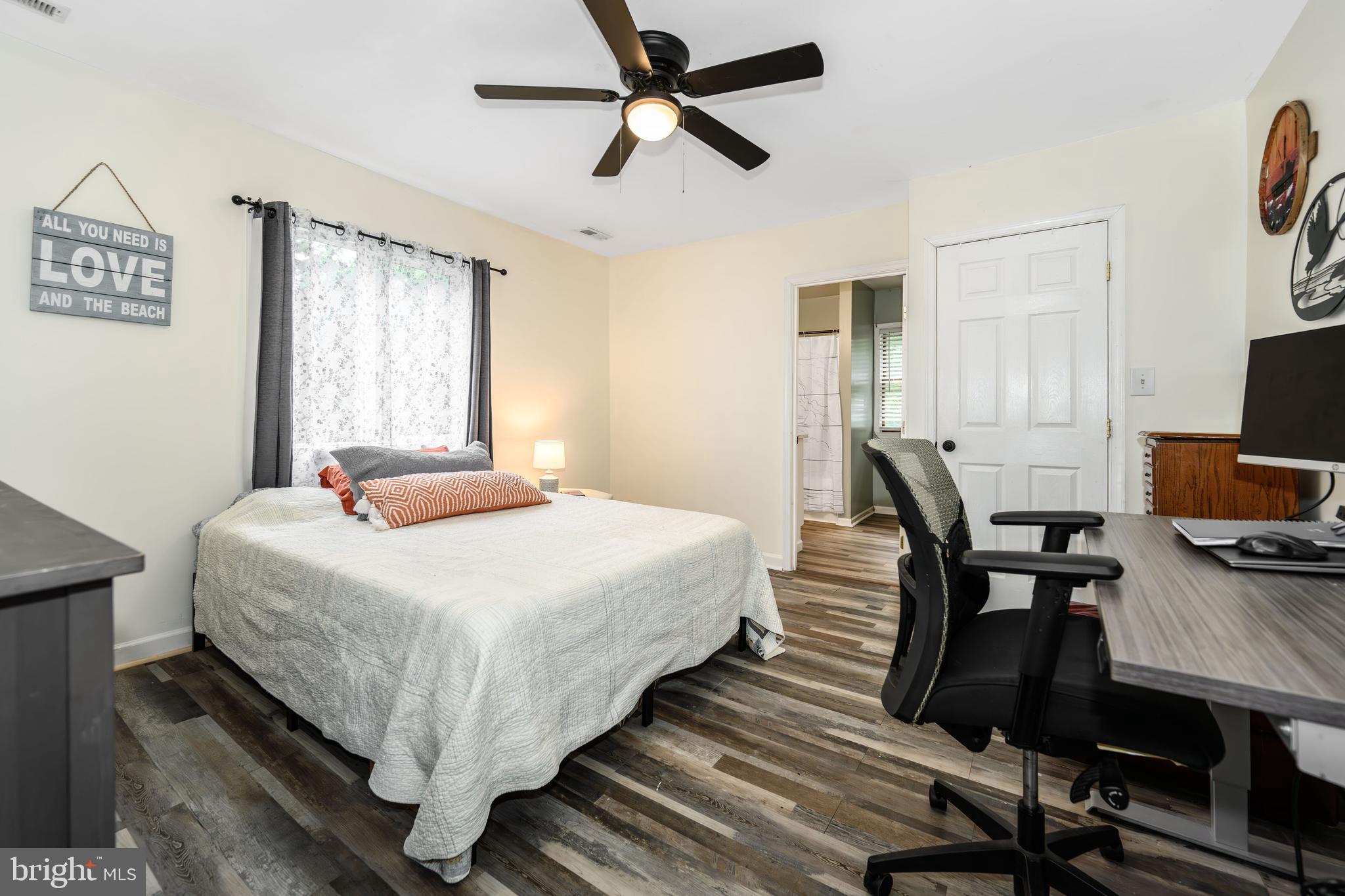 204 Long Point Road Stevensville, MD 21666 - Photo 17 of 34 a bedroom with a bed a desk and chair with wooden floor