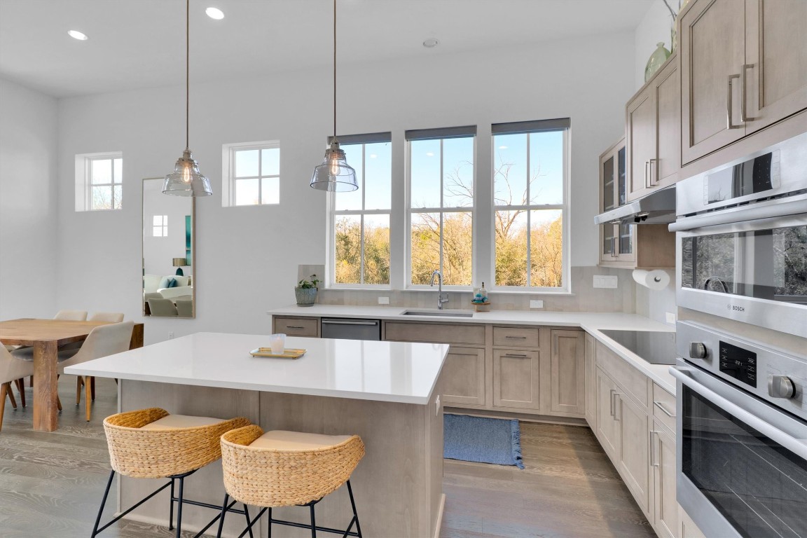 4806 Olive Sparrow Drive, Unit C Austin, TX 78723 - Photo 11 of 32 Kitchen featuring light wood-style floors, pendant lighting, a kitchen bar, appliances with stainless steel finishes, and a kitchen island
