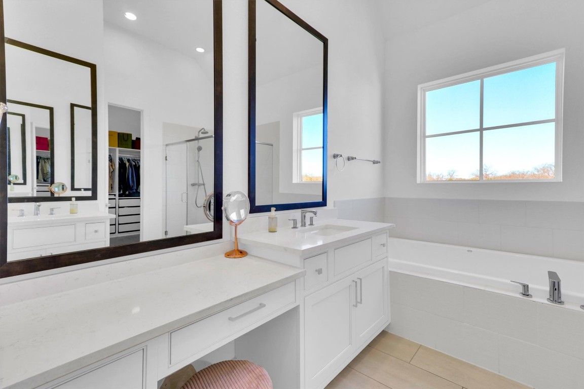 4806 Olive Sparrow Drive, Unit C Austin, TX 78723 - Photo 19 of 32 Full bathroom featuring two vanities, a garden tub, a spacious closet, light tile patterned floors, and recessed lighting