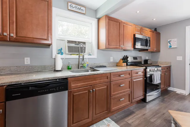 a kitchen with stainless steel appliances granite countertop a sink a stove a microwave cabinets and a window