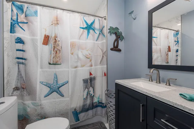 a bathroom with a granite countertop sink toilet and a mirror