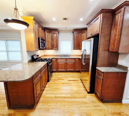 a large kitchen with stainless steel appliances granite countertop a refrigerator a sink dishwasher and wooden cabinets