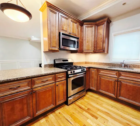 a kitchen with stainless steel appliances granite countertop a stove a sink and a microwave