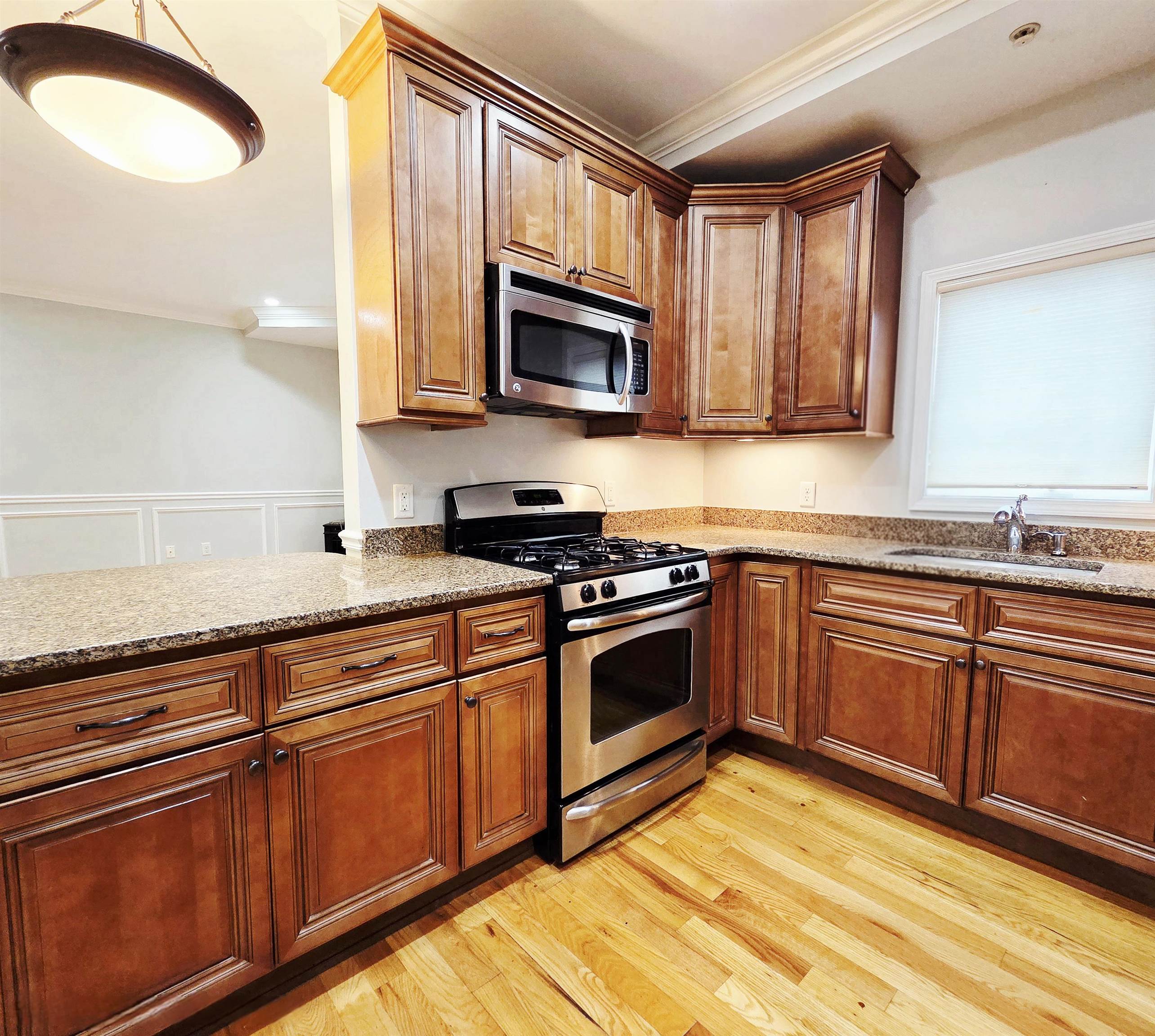 141 68th Street, Unit 7 Guttenberg, NJ 07093 - Photo 4 of 9 a kitchen with stainless steel appliances granite countertop a stove a sink and a microwave