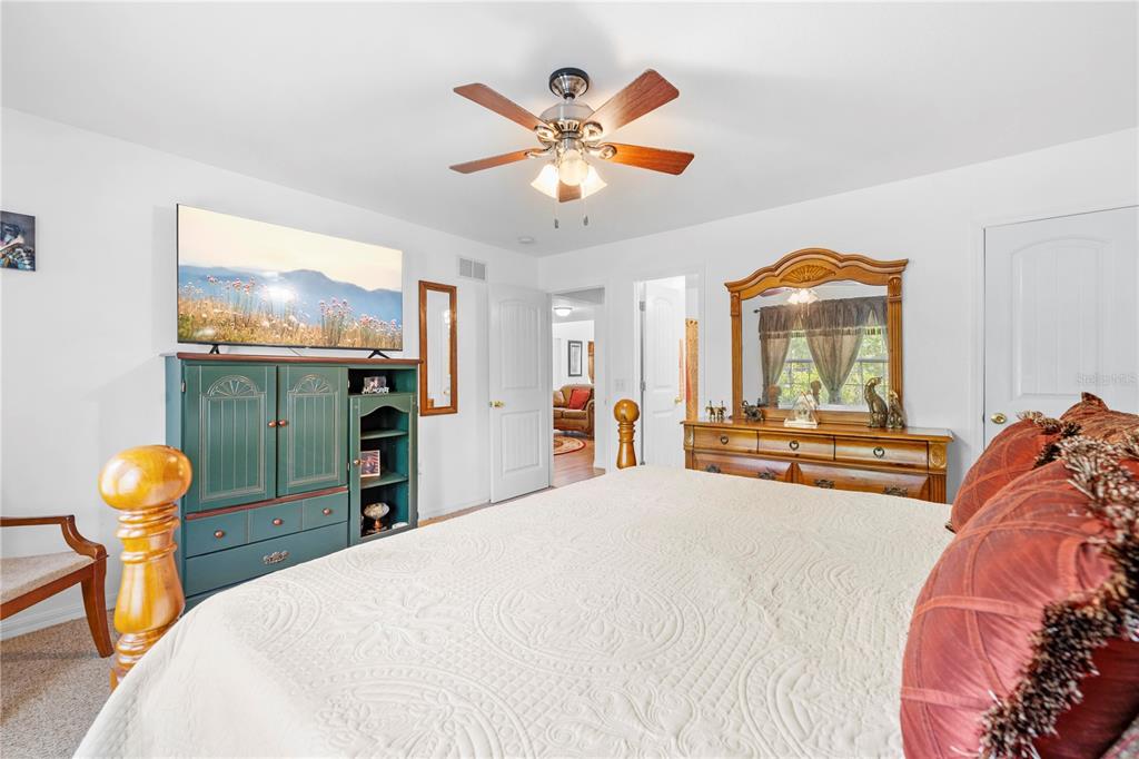7347 Packingham Drive Webster, FL 33597 - Photo 19 of 75 a bedroom with a bed and a chandelier with a flat tv screen