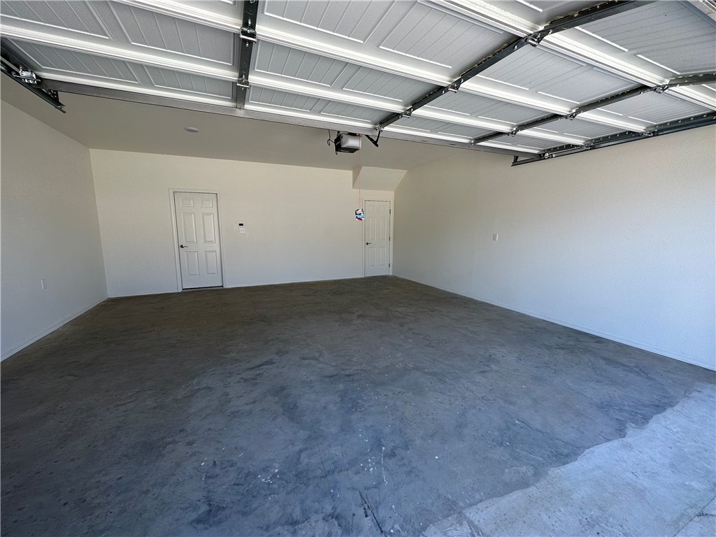 The property includes an expansive garage with concrete flooring, two white panel doors, and an exposed overhead door mechanism