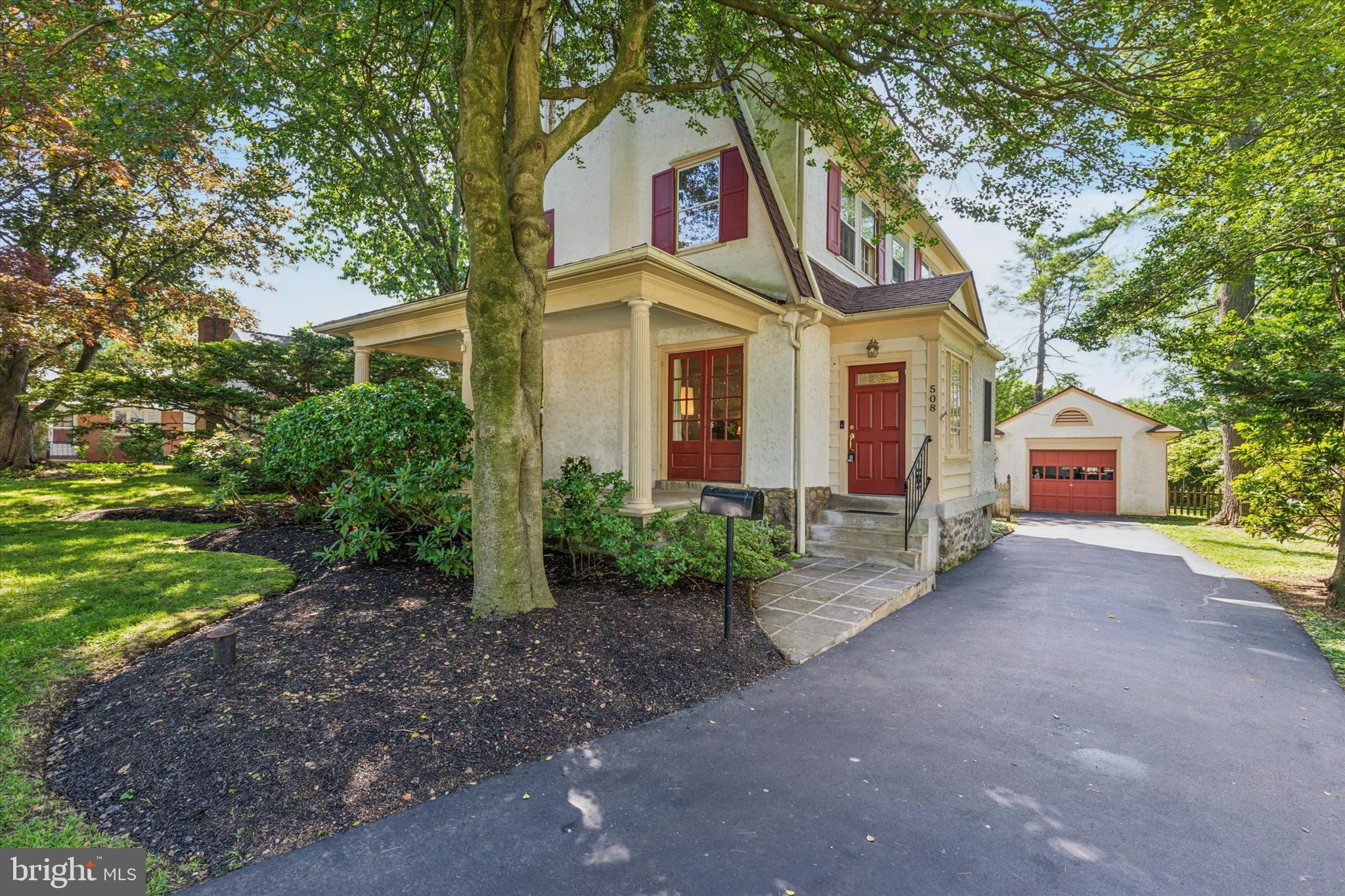 508 Baird Road Merion Station, PA 19066 - Photo 2 of 52 a view of a white house with large trees and plants next to a road