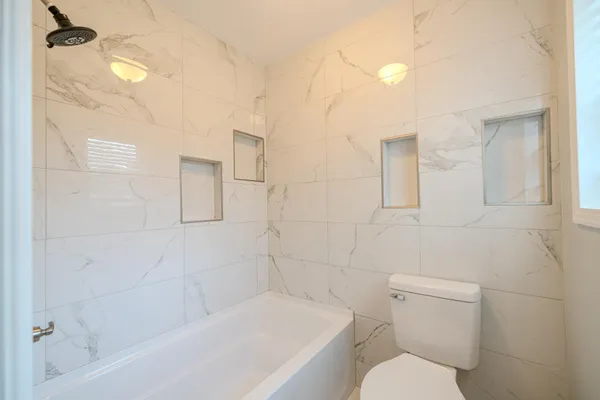 a white toilet sitting next to a bath tub