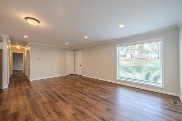 a view of an empty room with wooden floor and a window