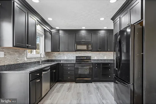 a large kitchen with stainless steel appliances granite countertop a stove a sink and a refrigerator