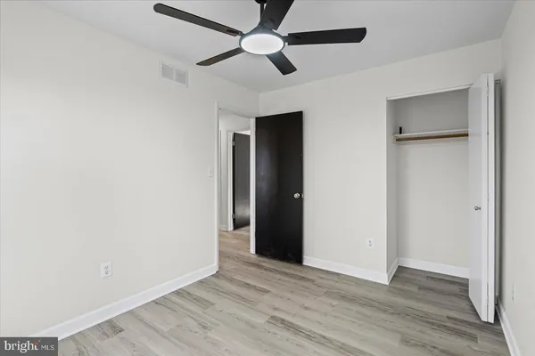an empty room with wooden floor a ceiling fan and closet