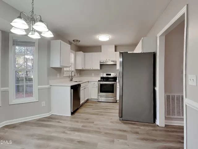 a kitchen with stainless steel appliances granite countertop a refrigerator a sink dishwasher a stove and a refrigerator