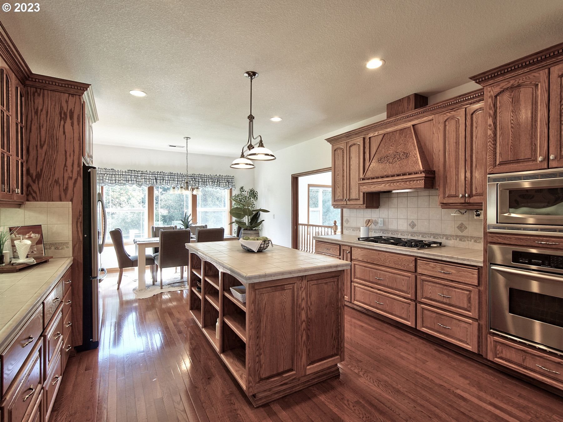 1101 Northeast 264th Street Ridgefield, WA 98642 - Photo 8 of 48 a kitchen with stainless steel appliances granite countertop a stove a sink dishwasher a refrigerator and a dining table with wooden floor