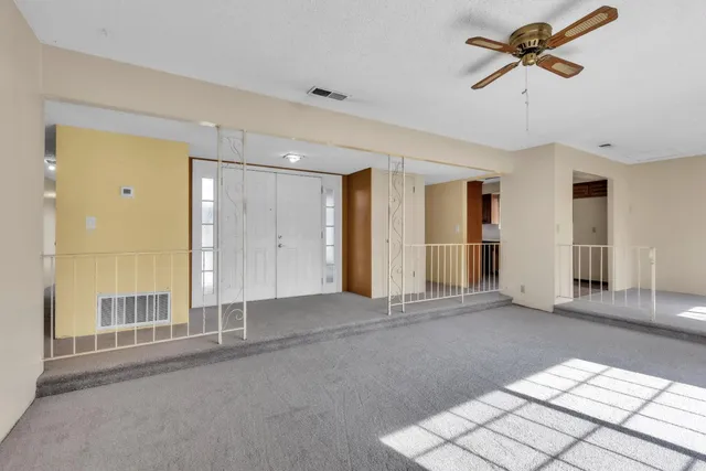 a view of a livingroom with a chandelier fan and windows