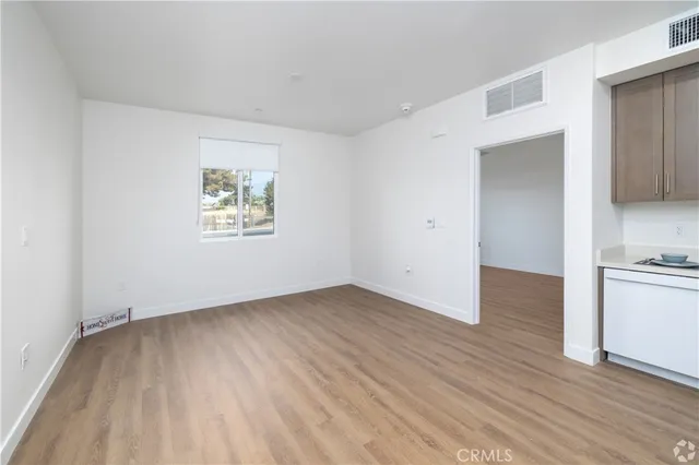 an empty room with wooden floor cabinet and windows