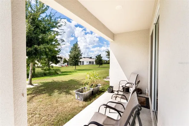 a view of a patio with lawn chairs floor to ceiling window and yard
