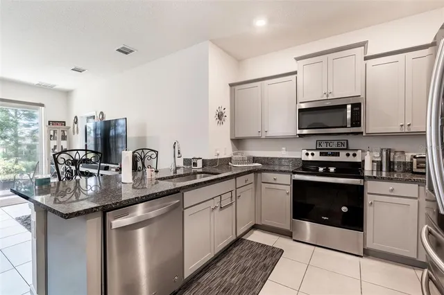 a kitchen with stainless steel appliances granite countertop a stove a sink and a microwave