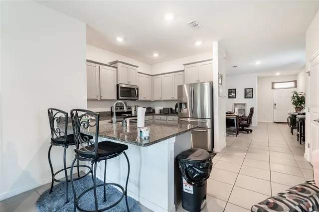 a kitchen with stainless steel appliances kitchen island granite countertop a refrigerator and microwave