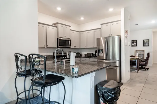 a kitchen with stainless steel appliances granite countertop a refrigerator a stove a sink a dining table and chairs