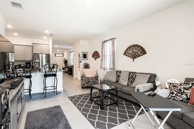 a living room with furniture a rug and white kitchen