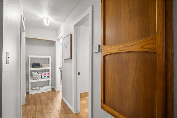 a view of a hallway with wooden floor and a bathroom