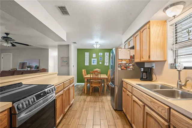 a kitchen with stainless steel appliances granite countertop a stove a sink dishwasher and a dining table with wooden floor
