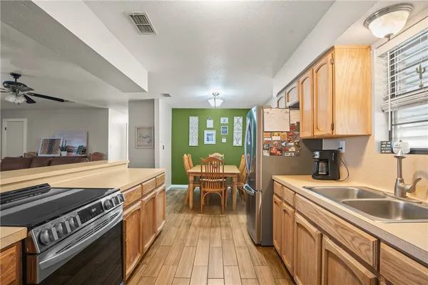 a kitchen with stainless steel appliances granite countertop a stove a sink dishwasher and a dining table with wooden floor